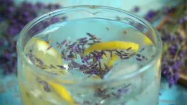 Taze lavanta çiçeklerinden limonata ve ahşap bir arka planda limon hazırlamak. Yavaş çekim.