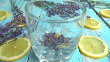 Taze lavanta çiçeklerinden limonata, ahşap bir arka planda limon. Kaynar su bir bardağa dökülür. Yavaş çekim.