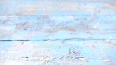 Bouquet of fresh roses flowers drops on vintage wooden light blue surface. Slow motion.