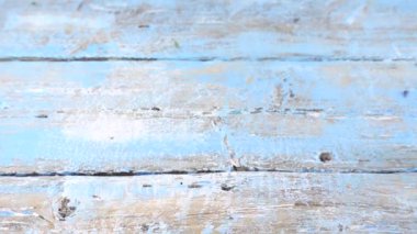 Colorful summer garden flowers: a bouquet of lilac sweet peas falls on a vintage wooden blue surface. Slow motion.