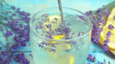 Taze lavanta çiçeklerinden limonata ve ahşap bir arka planda limon hazırlamak. Yavaş çekim.