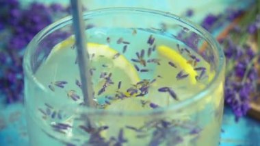 Taze lavanta çiçeklerinden limonata ve ahşap bir arka planda limon hazırlamak. Yavaş çekim.