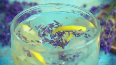 Taze lavanta çiçeklerinden limonata ve ahşap bir arka planda limon hazırlamak. Yavaş çekim.