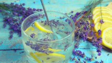 Taze lavanta çiçeklerinden limonata ve ahşap bir arka planda limon hazırlamak. Yavaş çekim.