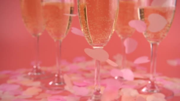 Falling Confetti Form Hearts Background Glasses Sparkling Wine Pink Background — Stockvideo