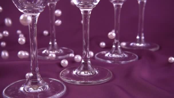 Falling White Pearls Next Wine Glasses Purple Background Slow Motion — Αρχείο Βίντεο