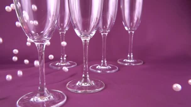 Falling White Pearls Next Wine Glasses Purple Background Slow Motion — Αρχείο Βίντεο