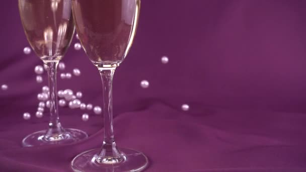 Falling White Pearls Next Wine Glasses Purple Background Slow Motion — Αρχείο Βίντεο