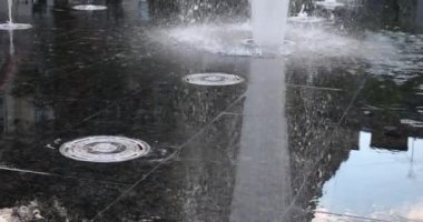 Children cool off in the jets of the fountain in the summer in the city. Slow motion.