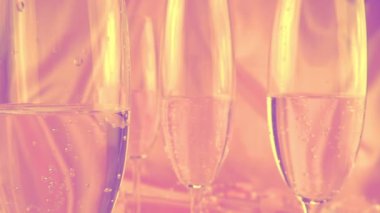 Köpüklü şarapla bardakların üzerine kalp şeklinde konfeti düşmesi, pembe arka planda hindistan cevizi taneli yuvarlak şeker. Yavaş çekim.