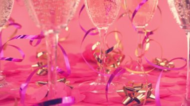 Pembe arka planda köpüklü şarap, kalp ve yılan şeklinde konfeti..