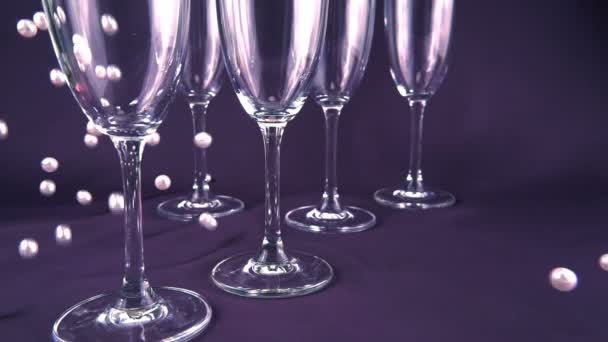 Falling White Pearls Next Wine Glasses Purple Background Slow Motion — Αρχείο Βίντεο