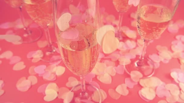 Falling Confetti Form Hearts Background Glasses Sparkling Wine Pink Background — Video Stock