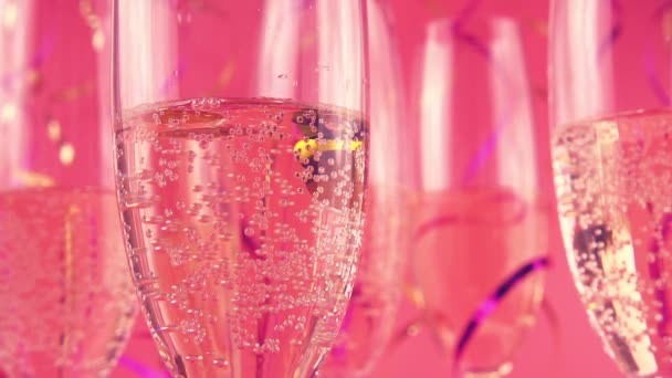 Vallende Confetti Glazen Met Mousserende Wijn Een Roze Achtergrond Langzame — Stockvideo