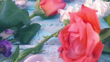 Colorful summer garden flowers: dragon flowers, roses, sweet pea on the vintage wooden light blue background.