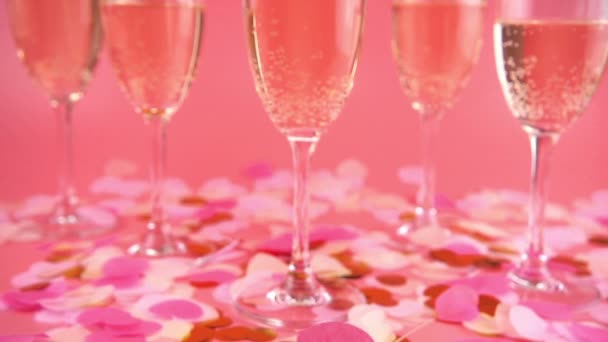 Falling Confetti Form Hearts Background Glasses Sparkling Wine Pink Background — Vídeo de stock