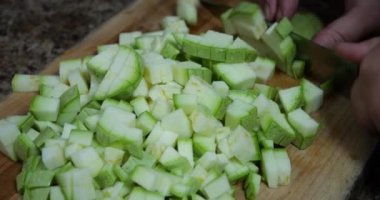Slicing zucchini on a cutting board.
