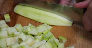 Slicing zucchini on a cutting board.
