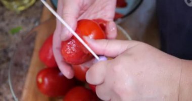 Peeling off the skins of red tomatoes.