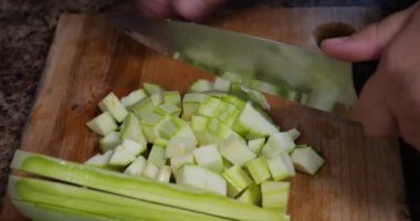 Slicing zucchini on a cutting board.