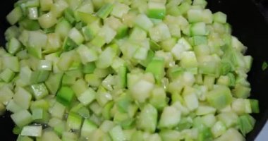 Cooking slices of zucchini in a pan.
