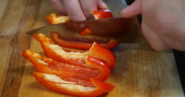 Slicing sweet red pepper on a cutting board.