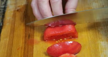 The cook cuts tomatoes on the kitchen board.