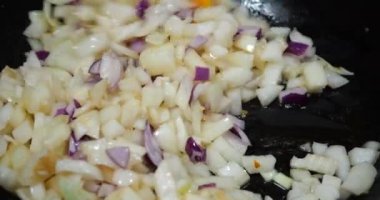 Onion pieces are fried in a pan.