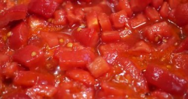 Pieces of tomatoes are fried in a pan.