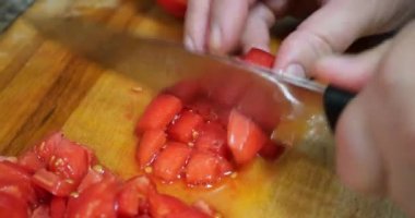 The cook cuts tomatoes on the kitchen board.