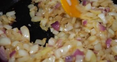 Onion pieces are fried in a pan.