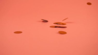 Falling confetti on a peach-pink background. Slow motion.