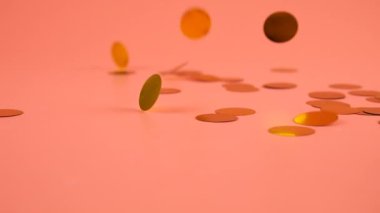 Falling confetti on a peach-pink background. Slow motion.