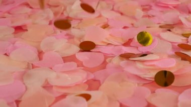 Falling confetti on a peach-pink background. Slow motion.