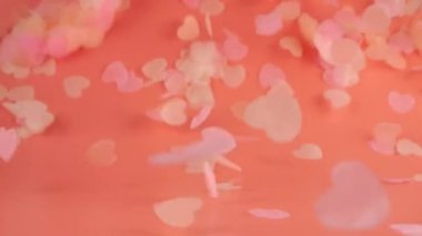 Flying confetti on a peach-pink background. slow motion.