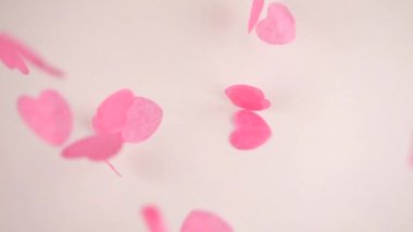 Falling confetti on a white background. Slow motion.