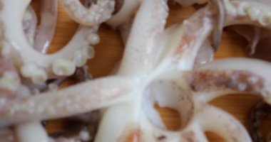 Tentacles with suction cups and carcass of raw squid on a cutting board. Fresh Seafood and Cooking.