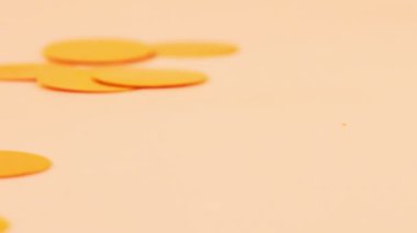 Falling confetti on a peach background. Slow motion.
