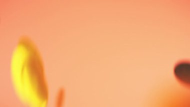 Falling confetti on a peach-pink background. Slow motion.