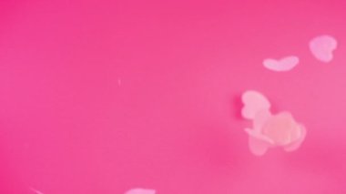 Falling confetti on a pink background. Slow motion.