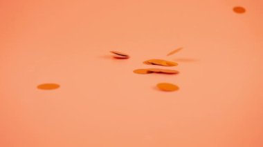 Falling confetti on a peach-pink background. Slow motion.