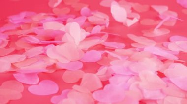 Falling confetti on a pink background. Slow motion.
