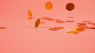 Falling confetti on a peach-pink background. Slow motion.