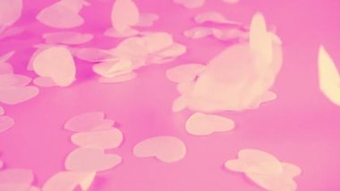 Falling confetti on a pink background. Slow motion.