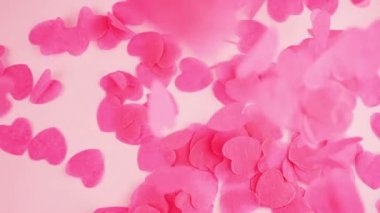 Falling confetti on a pink background. Slow motion.