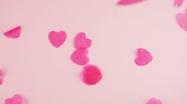 Falling confetti on a pink background. Slow motion.