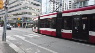 Modern trams, skyscrapers, streets and pedestrian crossing in downtown Toronto, Ontario, Canada.