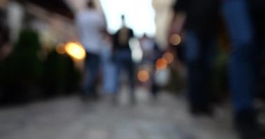 Garland lights and people in the evening cafe and on the street. European city architecture. Out of focus.