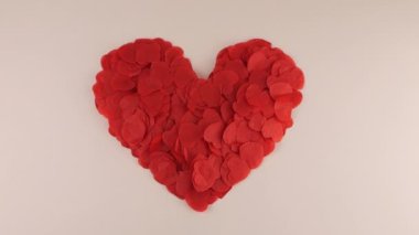 Heart-shaped confetti flies in the wind. Slow motion. Shooting on a white background.