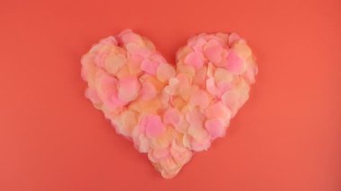 Heart-shaped confetti flies in the wind. Slow motion. Shooting on a pink background.